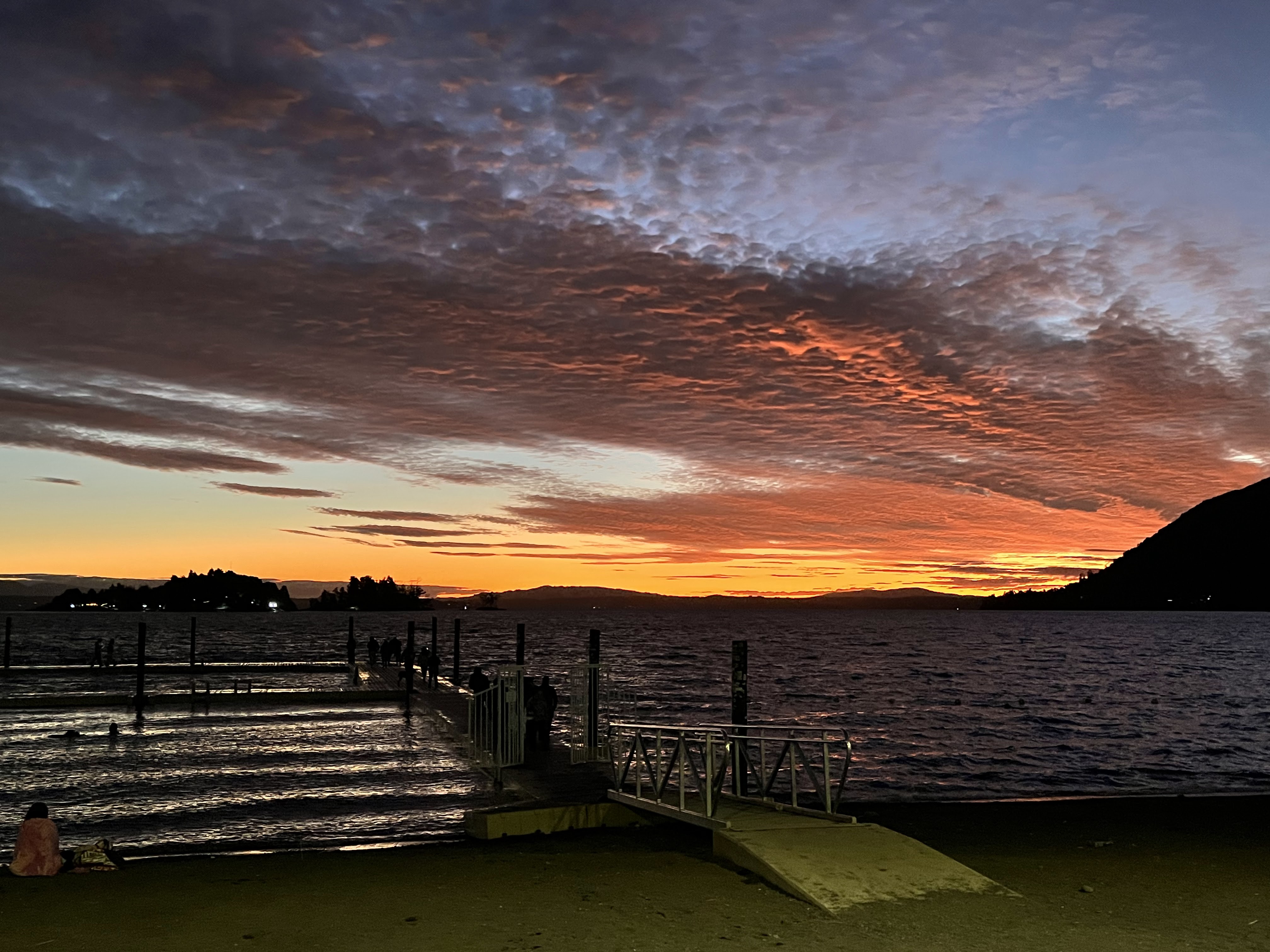 Atardecer sobre el lago con reflejos en la arena negra